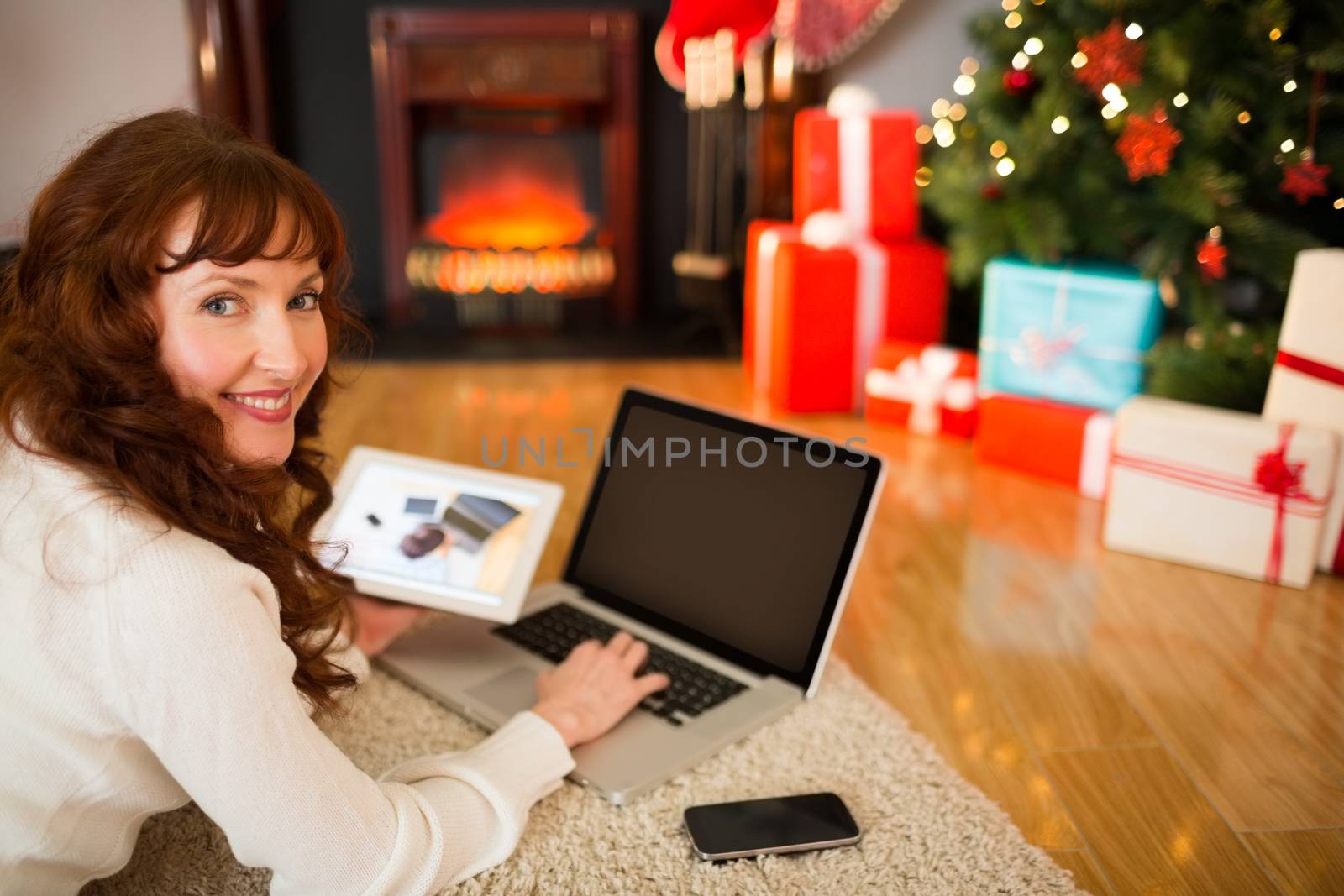 Pretty woman lying on floor using technology at Chritmas by Wavebreakmedia