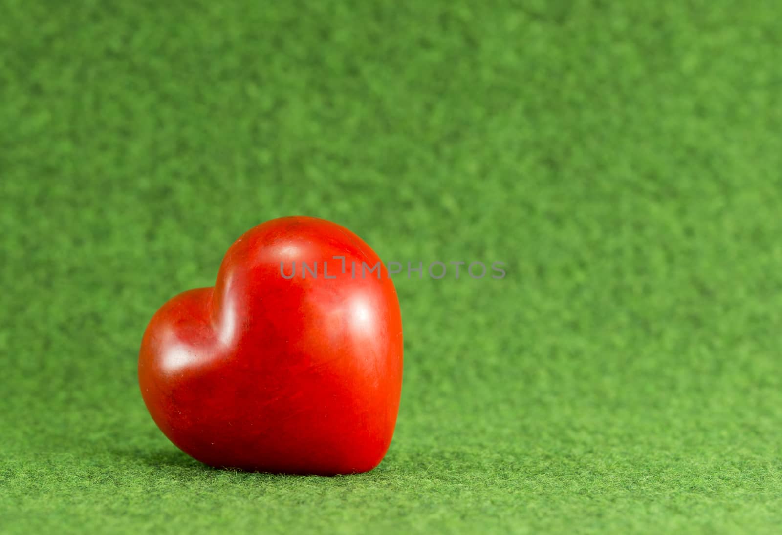 red heart on green grass background by compuinfoto