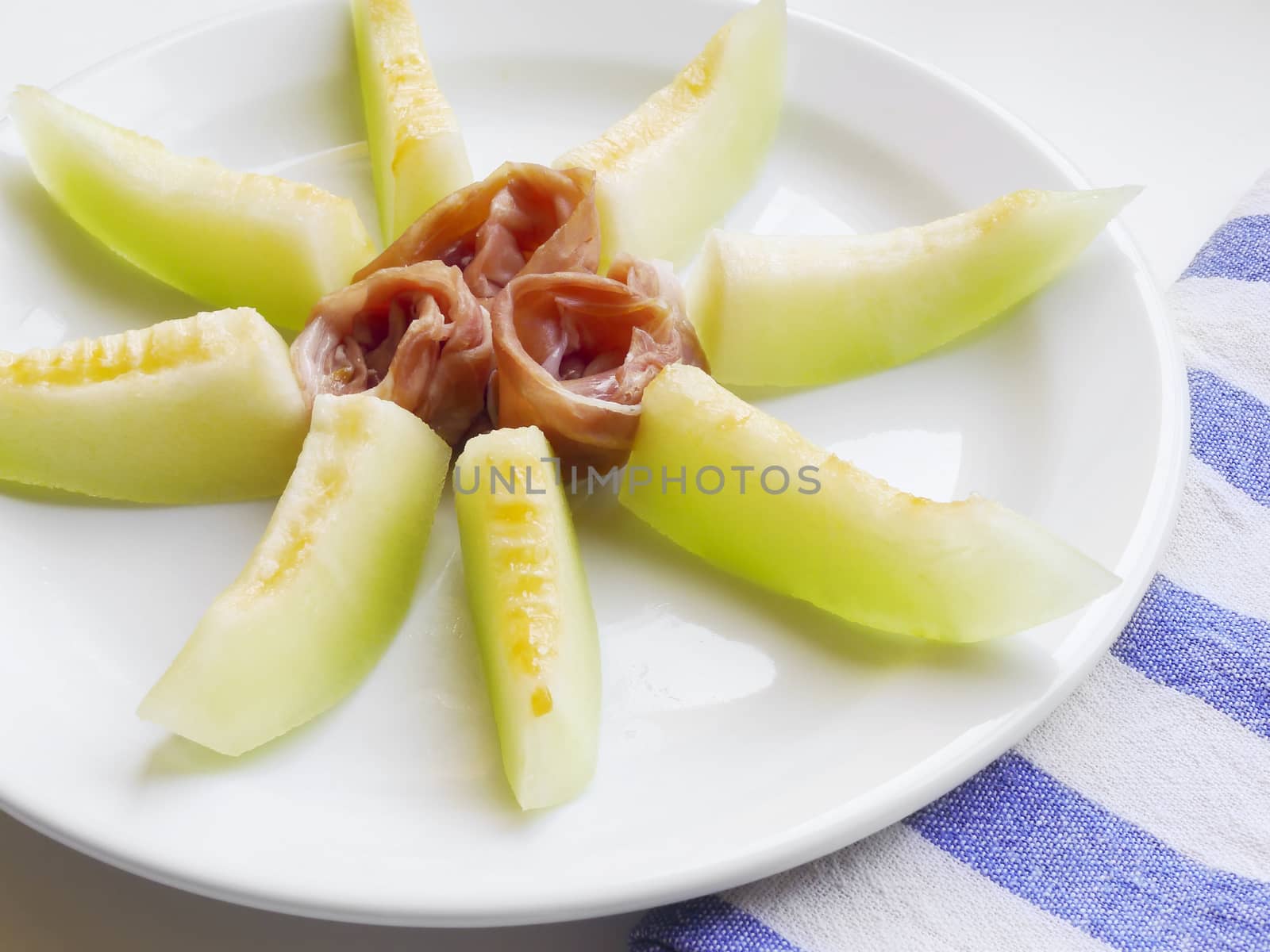 Fresh and juicy ham and melon sun shaped background. For delicious summer breakfast or lunch. 