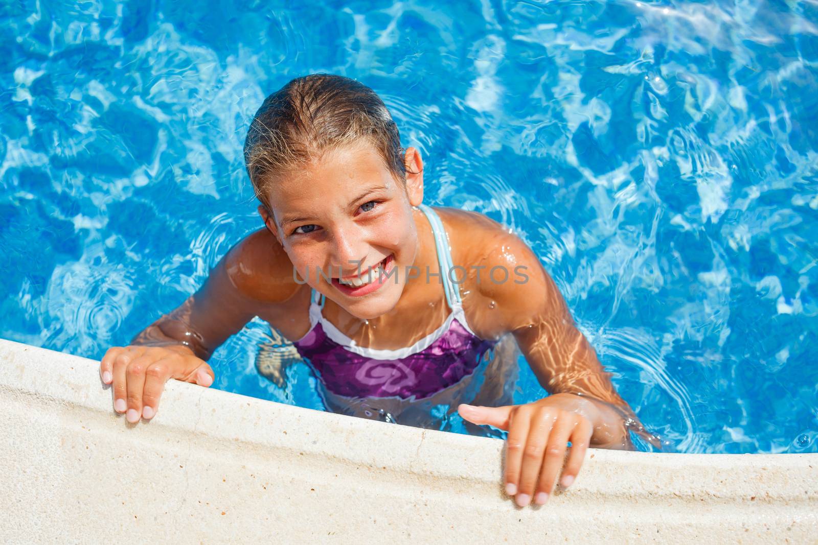 Cute happy young girl swimming and snorking in the swimming pool