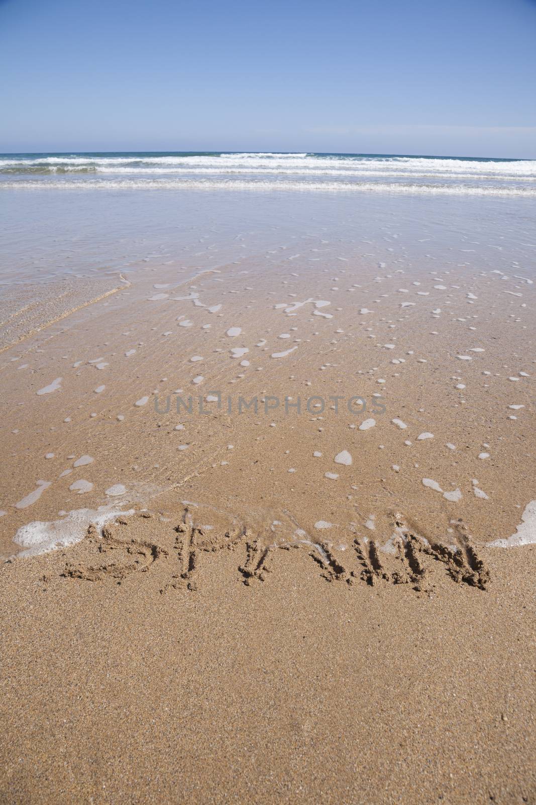 ocean water flood Spain word written on brown sand ground beach seashore