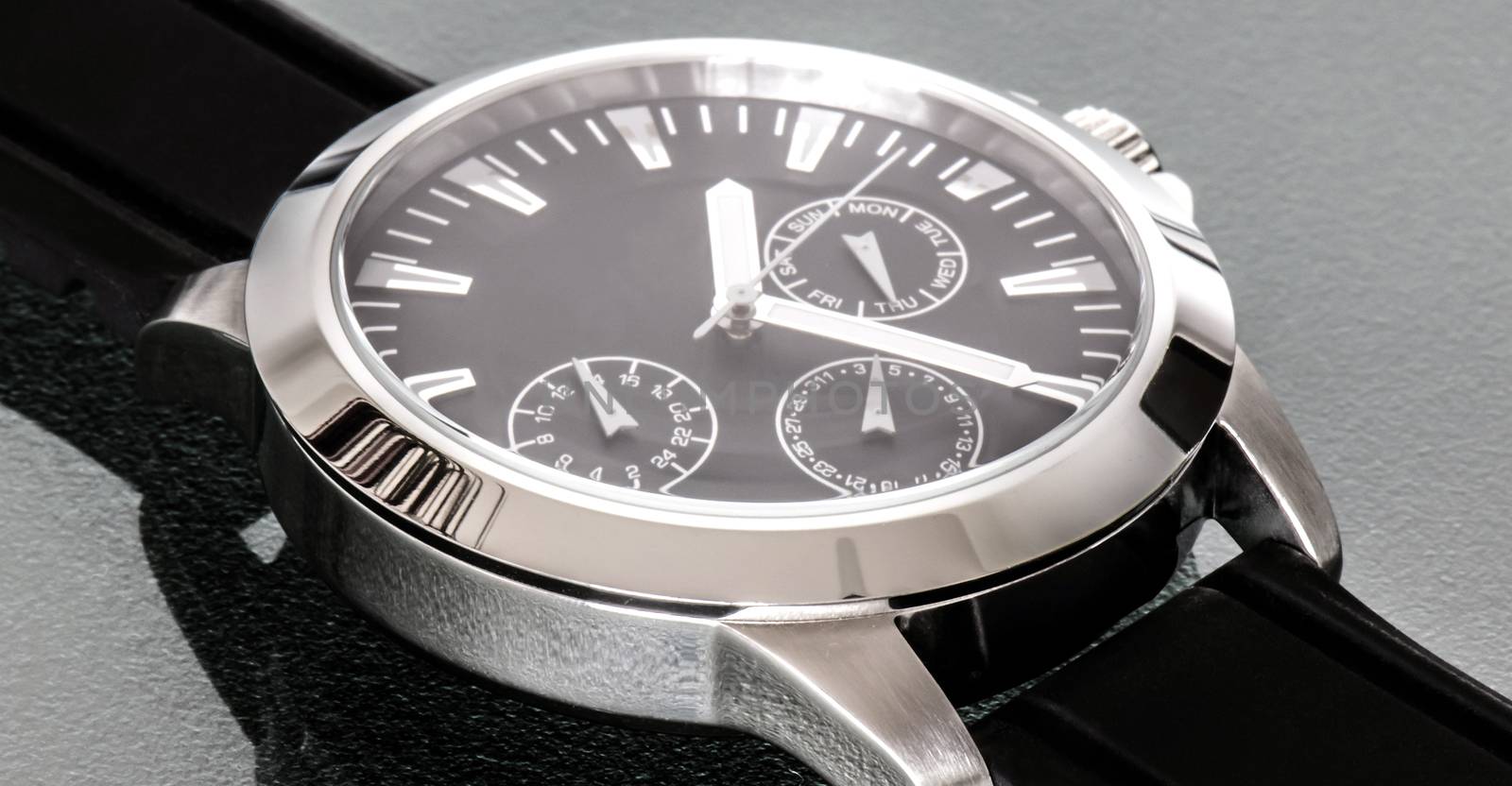 Silver colored stainless steel watch for men on a reflective background.