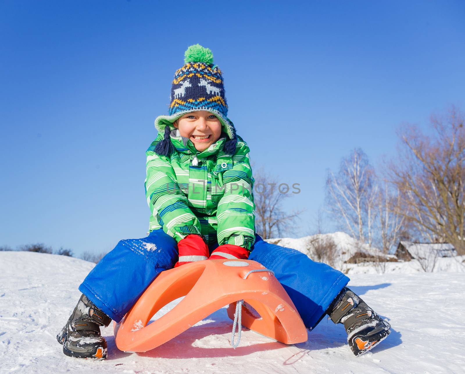 Little boy having fun with sled in winter park by maxoliki