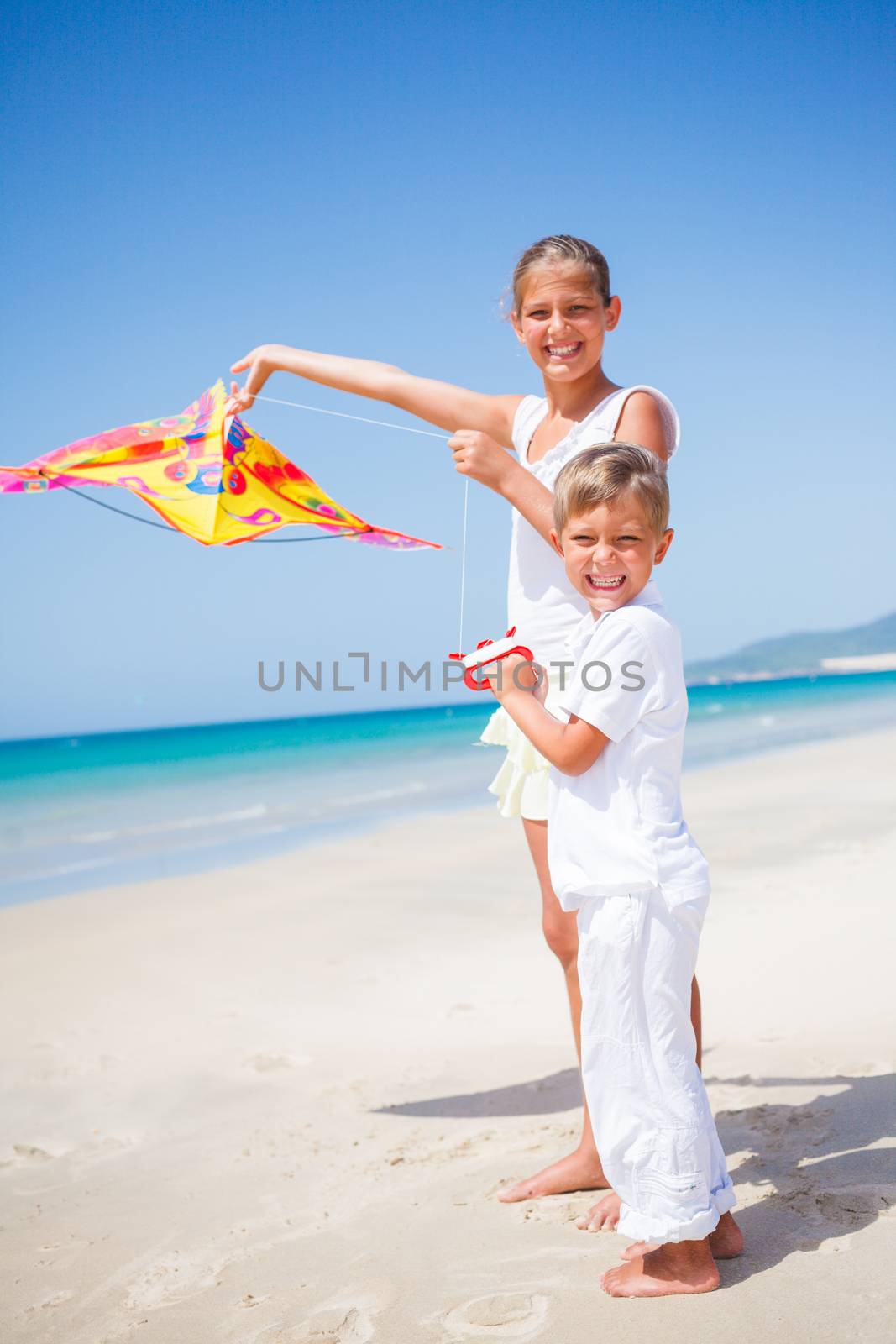 Summer vacation - Cute boy and girl flying kite beach outdoor.