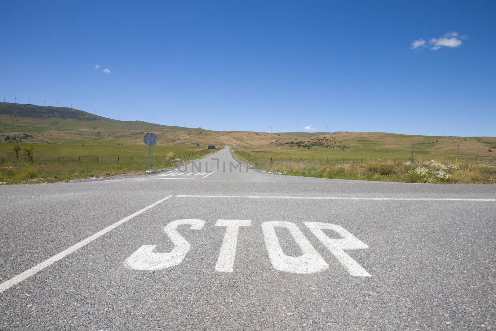 crossroad with stop symbol white painted on asphalt in rural road next to Madrid Spain Europe