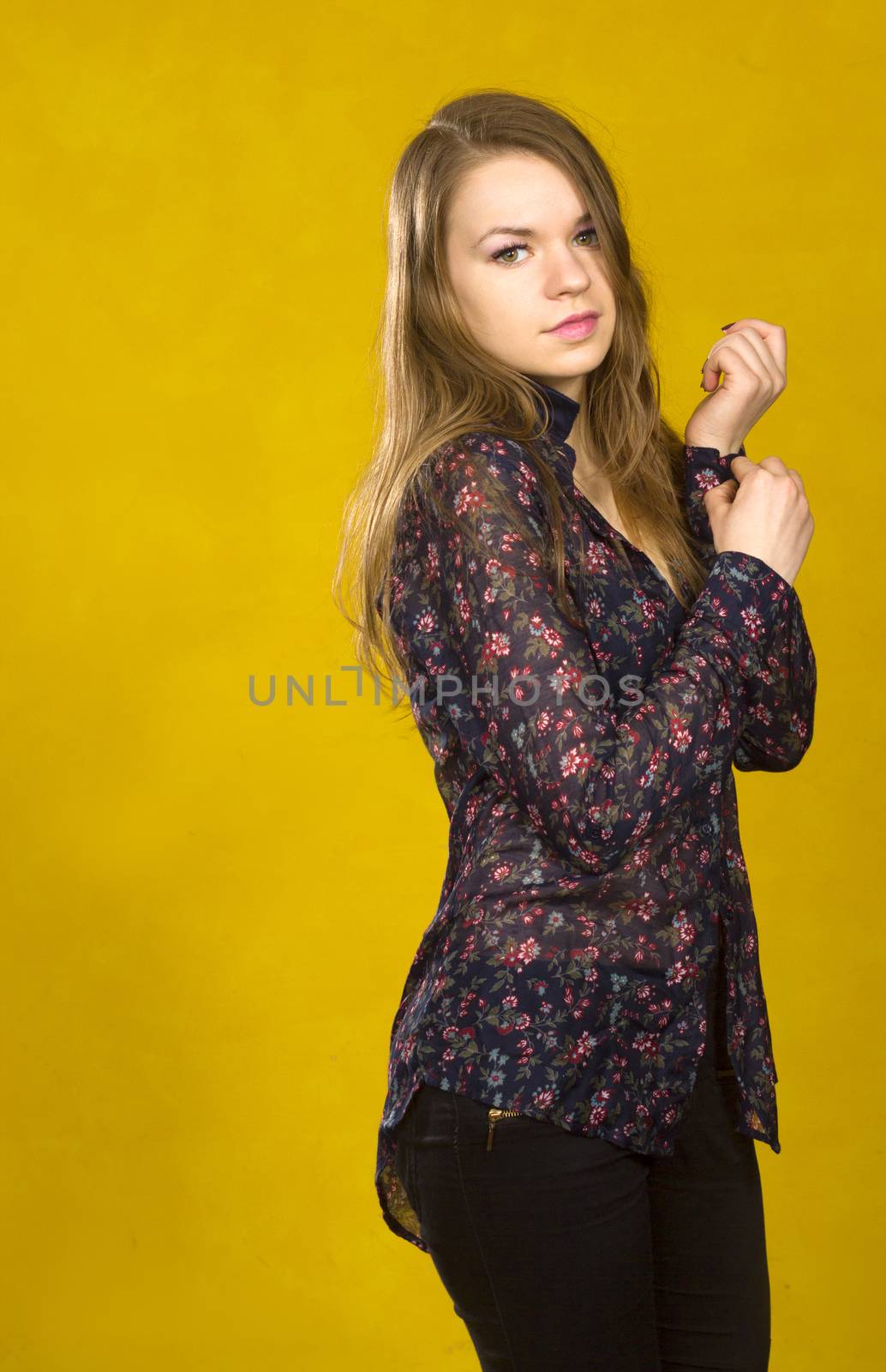 Woman buttoning on the sleeve. Yellow background. Space for text