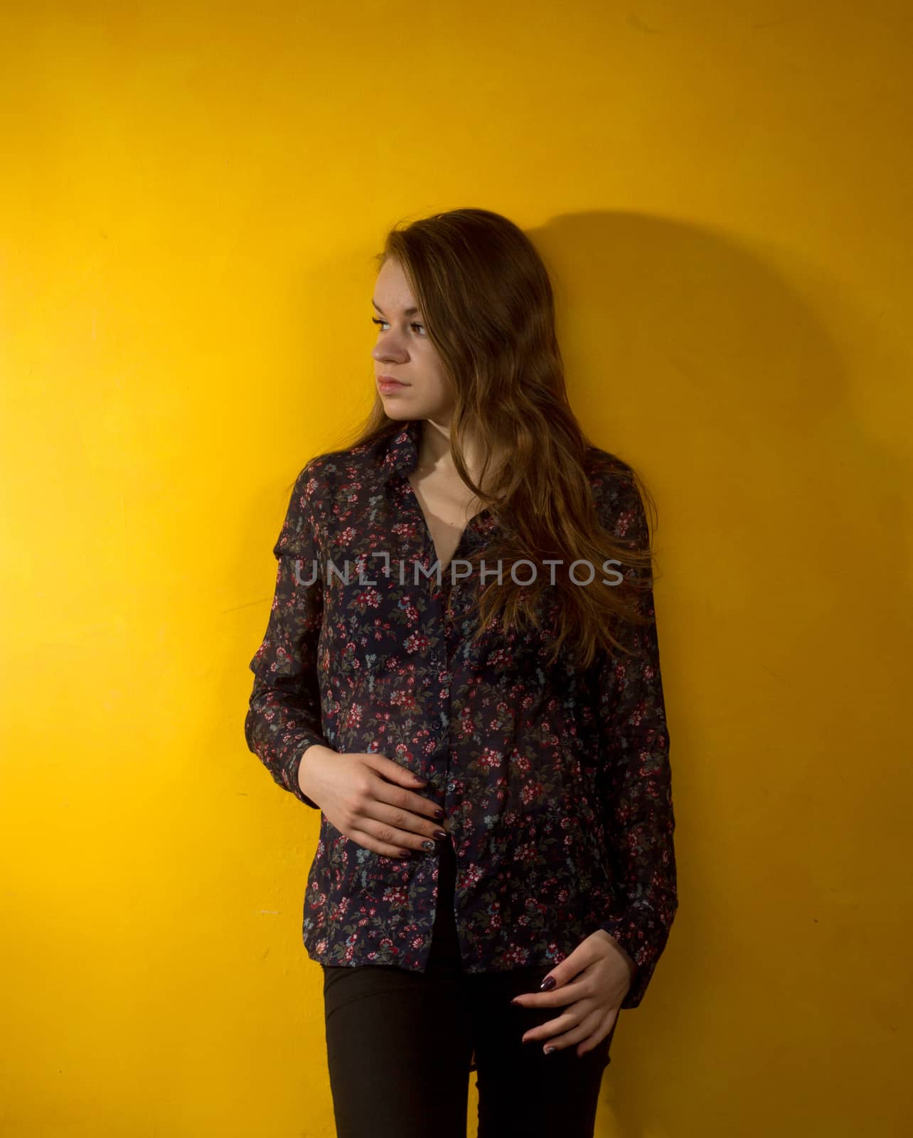 girl stands near the yellow wall. large shadow
