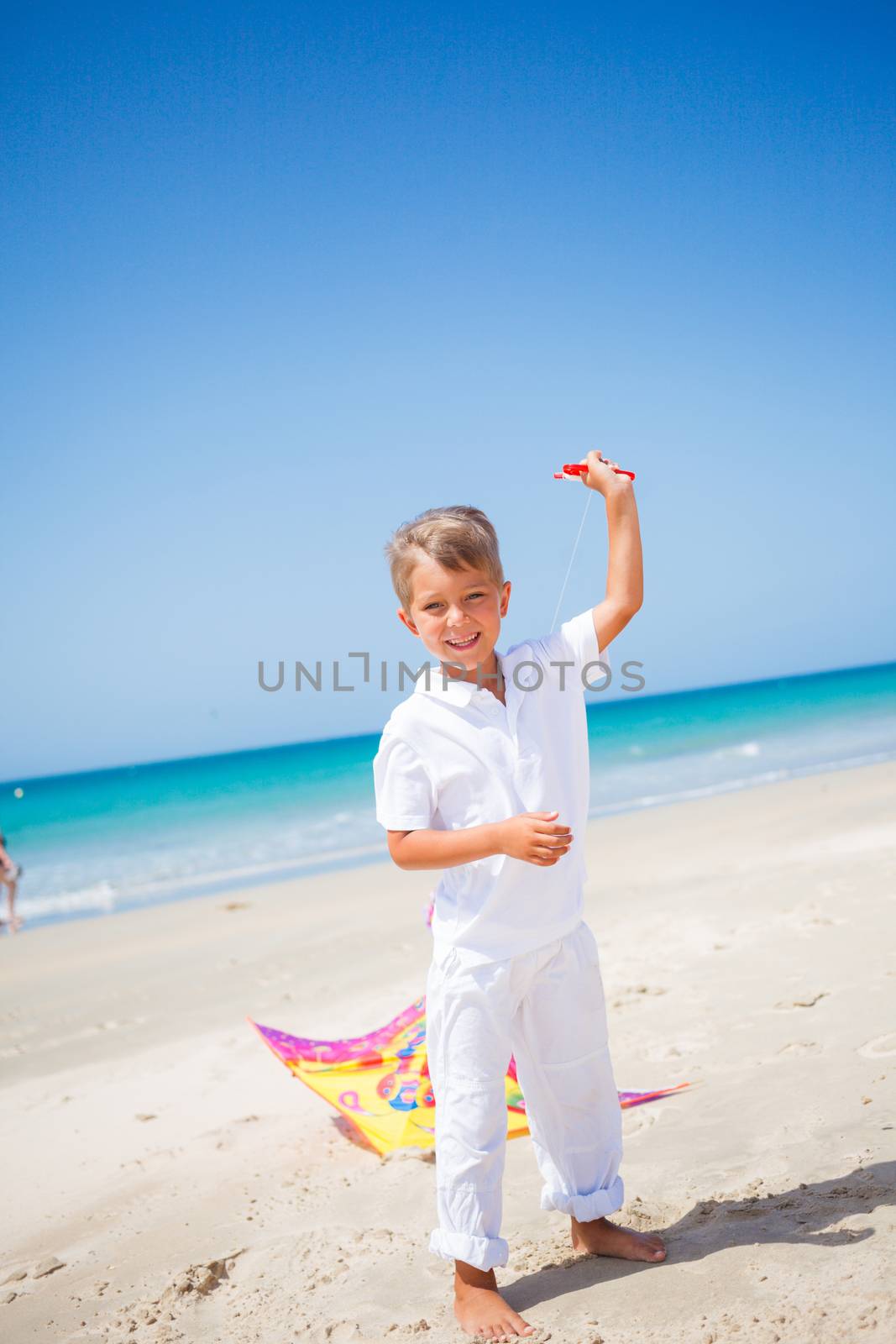 Summer vacation - Cute boy flying kite beach outdoor.