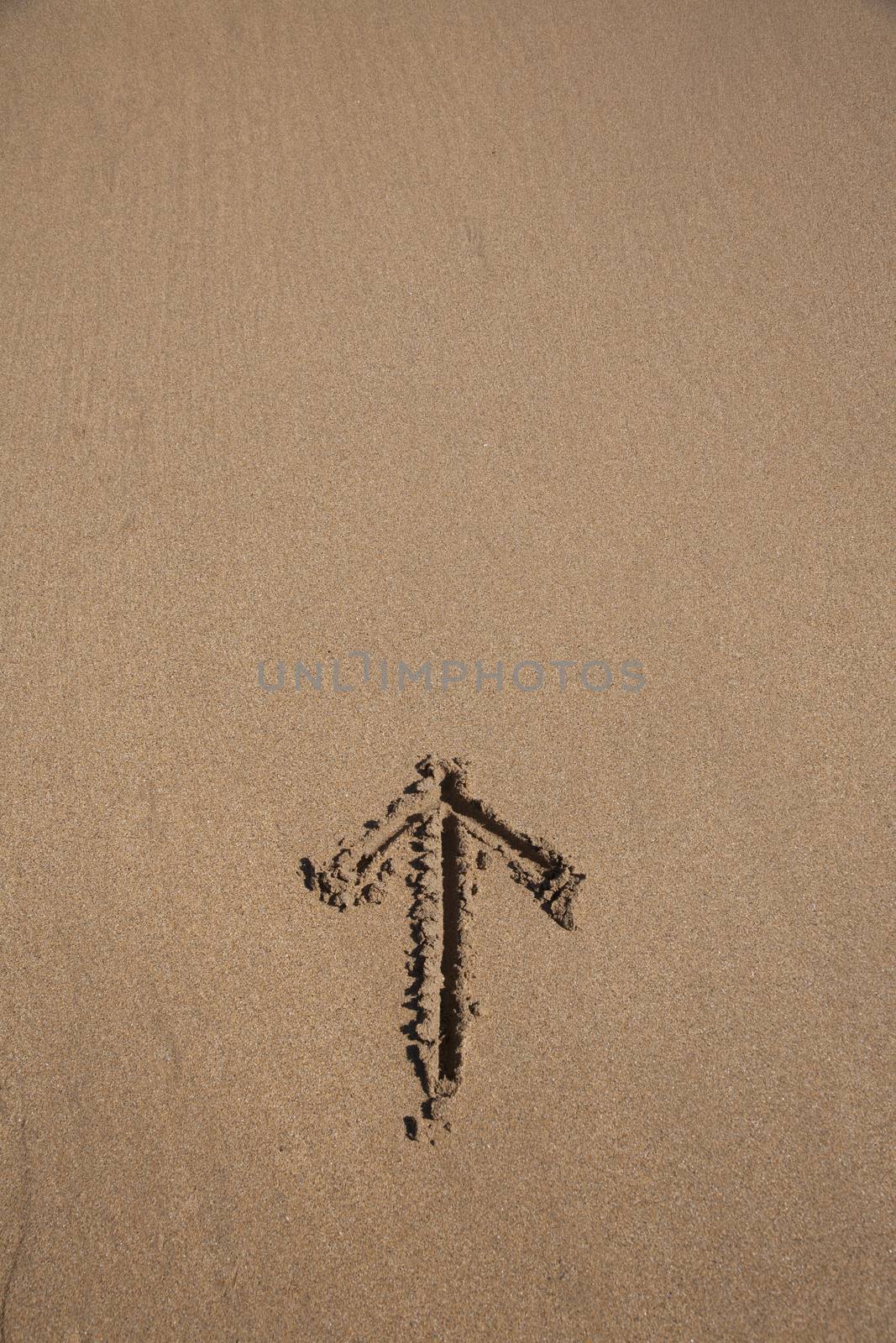 arrow drawn on brown sand ground low tide beach ocean seashore in Spain Europe