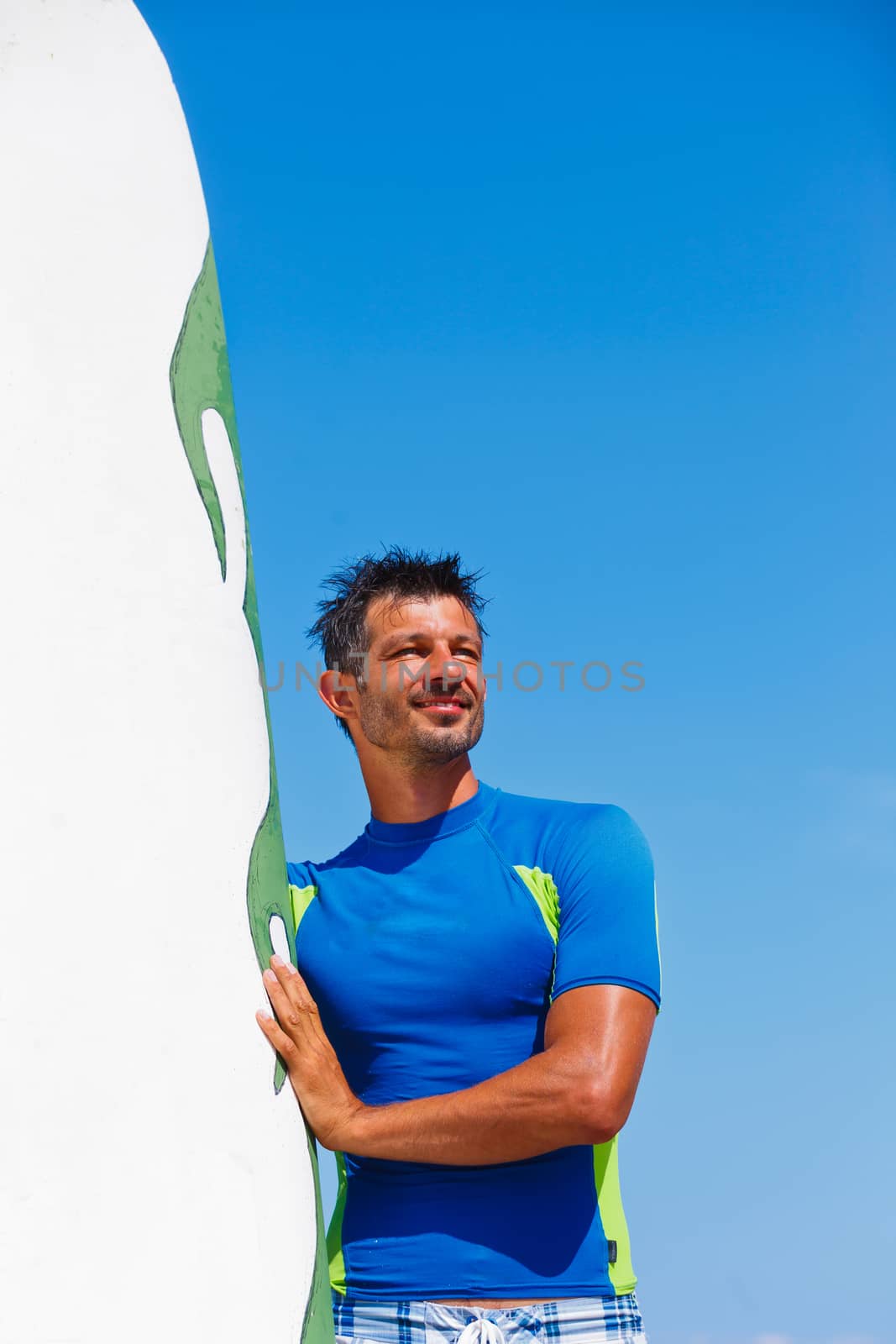 Strong young surf man at the beach with a surfboard.