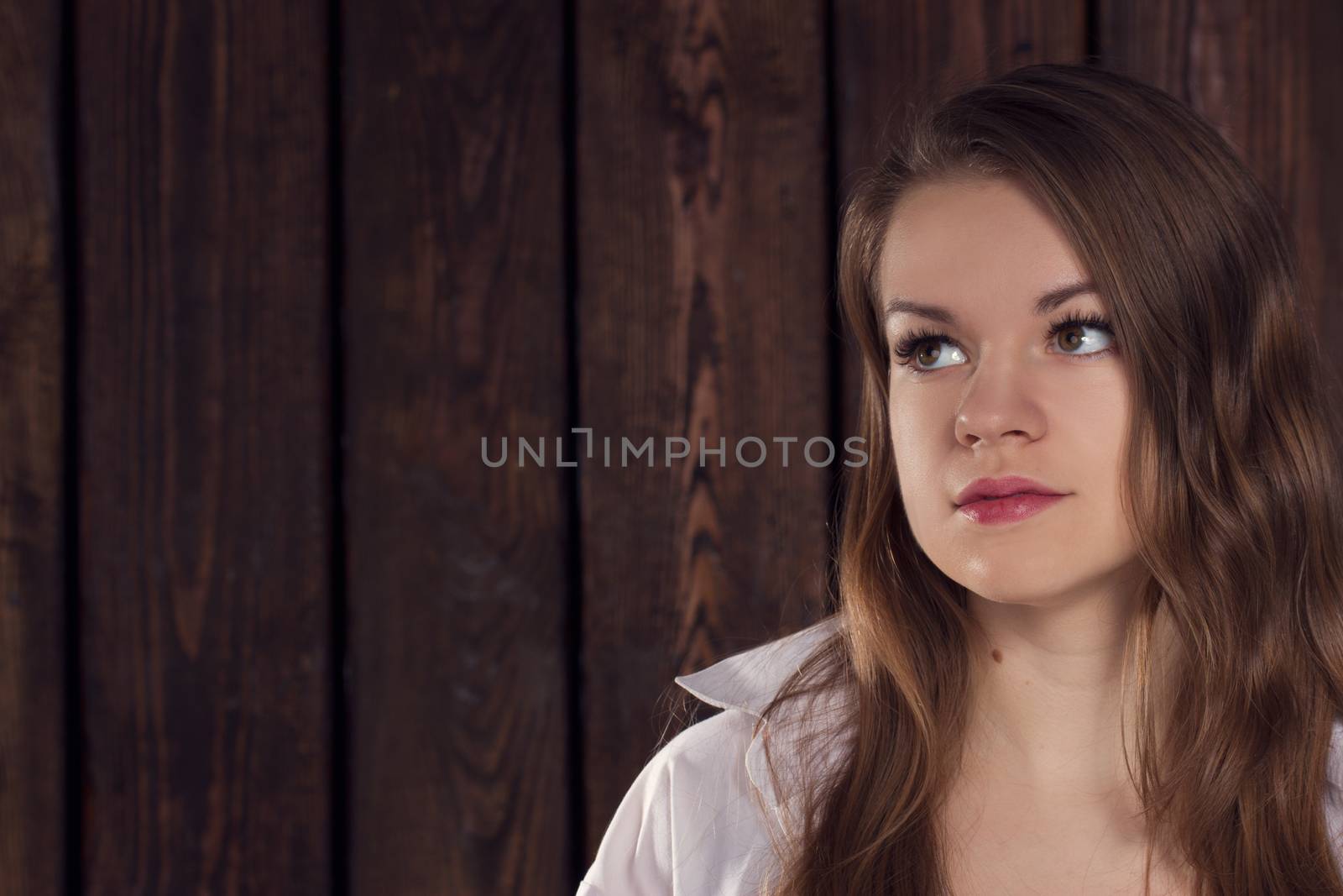 Portrait of a girl on a background of a wooden wall