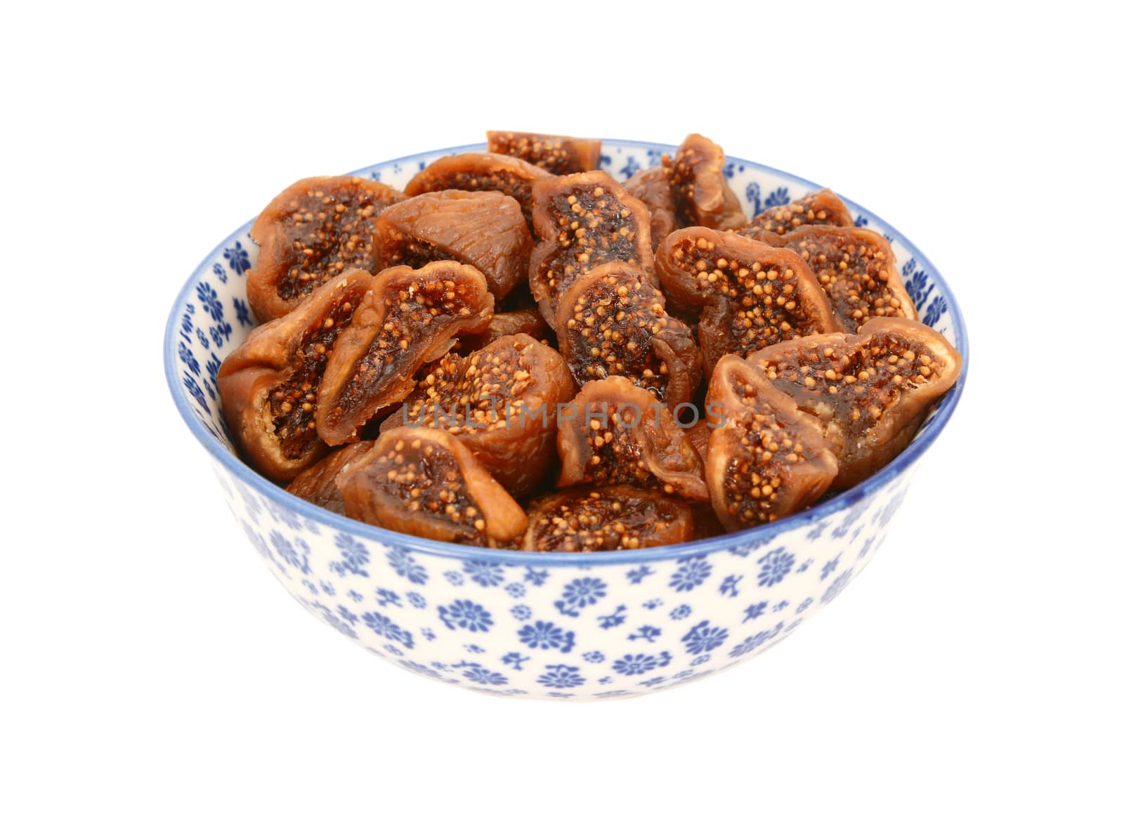 Chopped dried figs in a blue and white porcelain bowl with a floral design, isolated on a white background