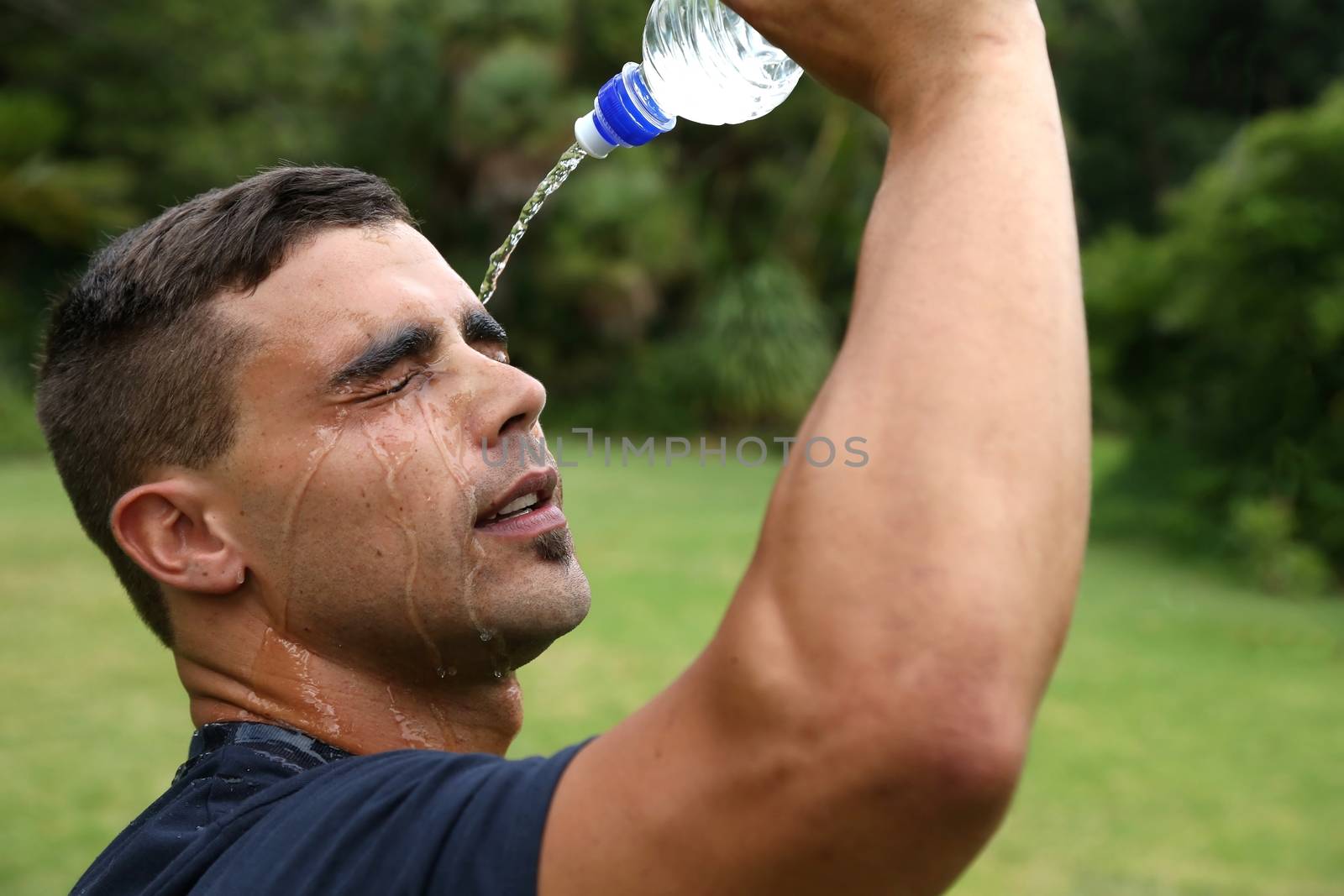 Handsome young exercise man pouring water on his face to cool down