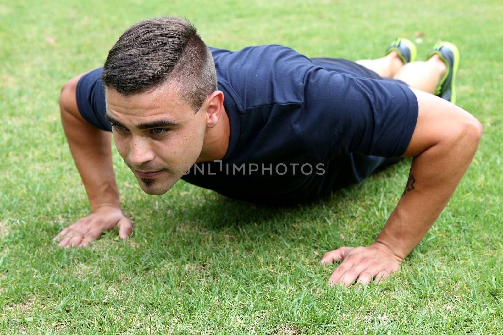 Handsome young man doing pushup exercises outdoors