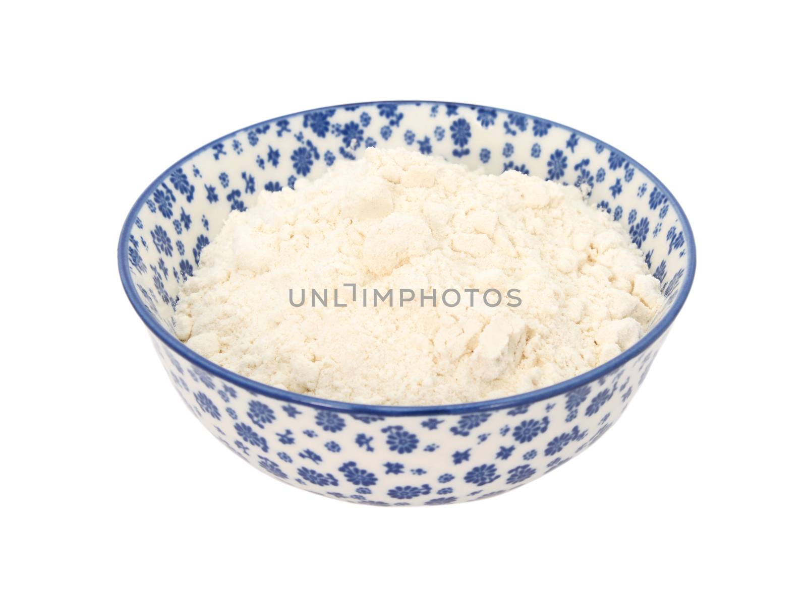 Plain or all purpose flour in a blue and white porcelain bowl with a floral design, isolated on a white background