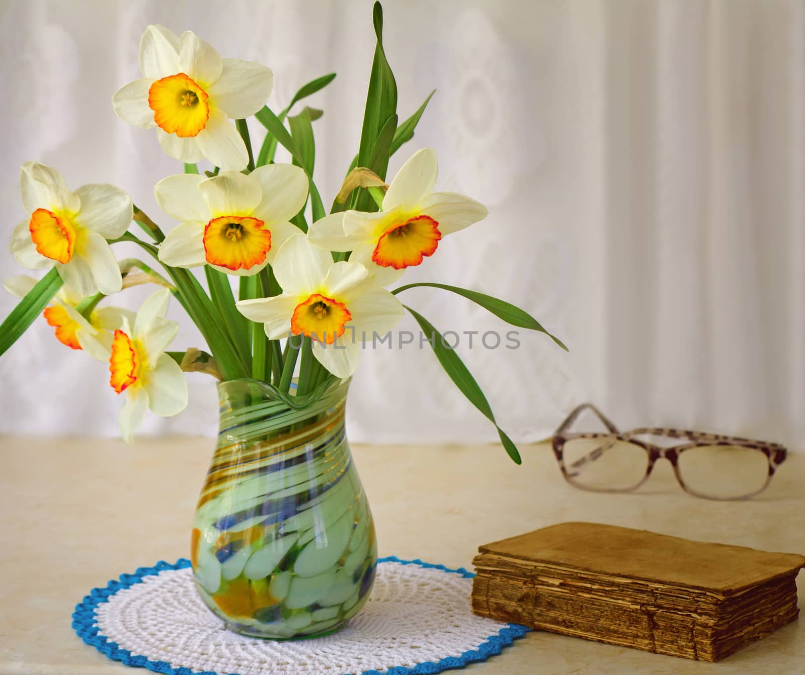 Blossoming narcissuses in a vase on a table. by georgina198