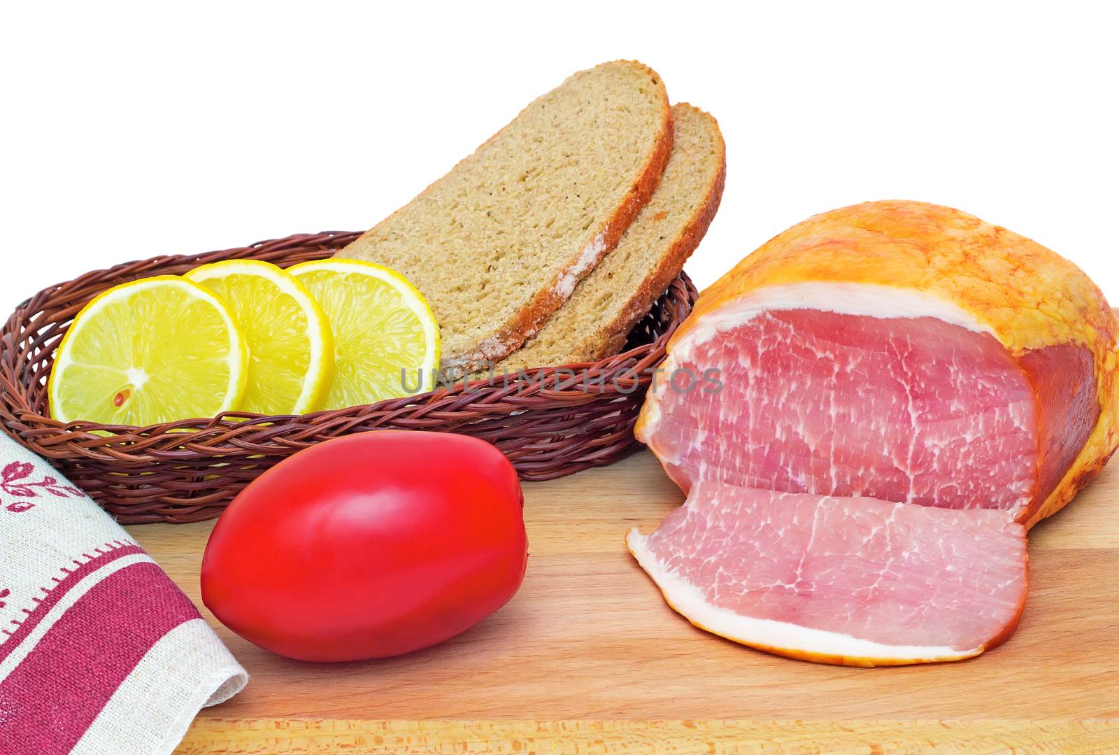 On a cutting Board is ham, bread, lemon and tomato. Presented on a white background.