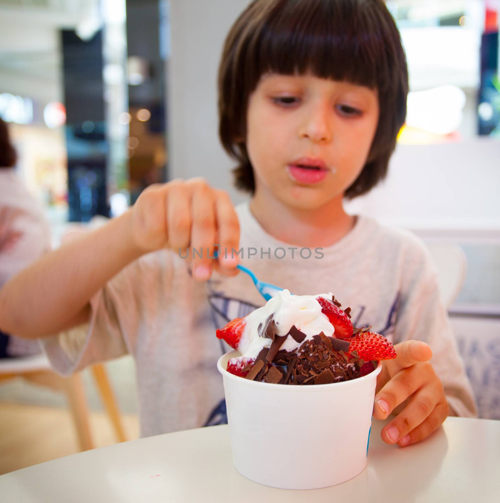 boy eating ice cream with chocolate and strawberries, editorial use only