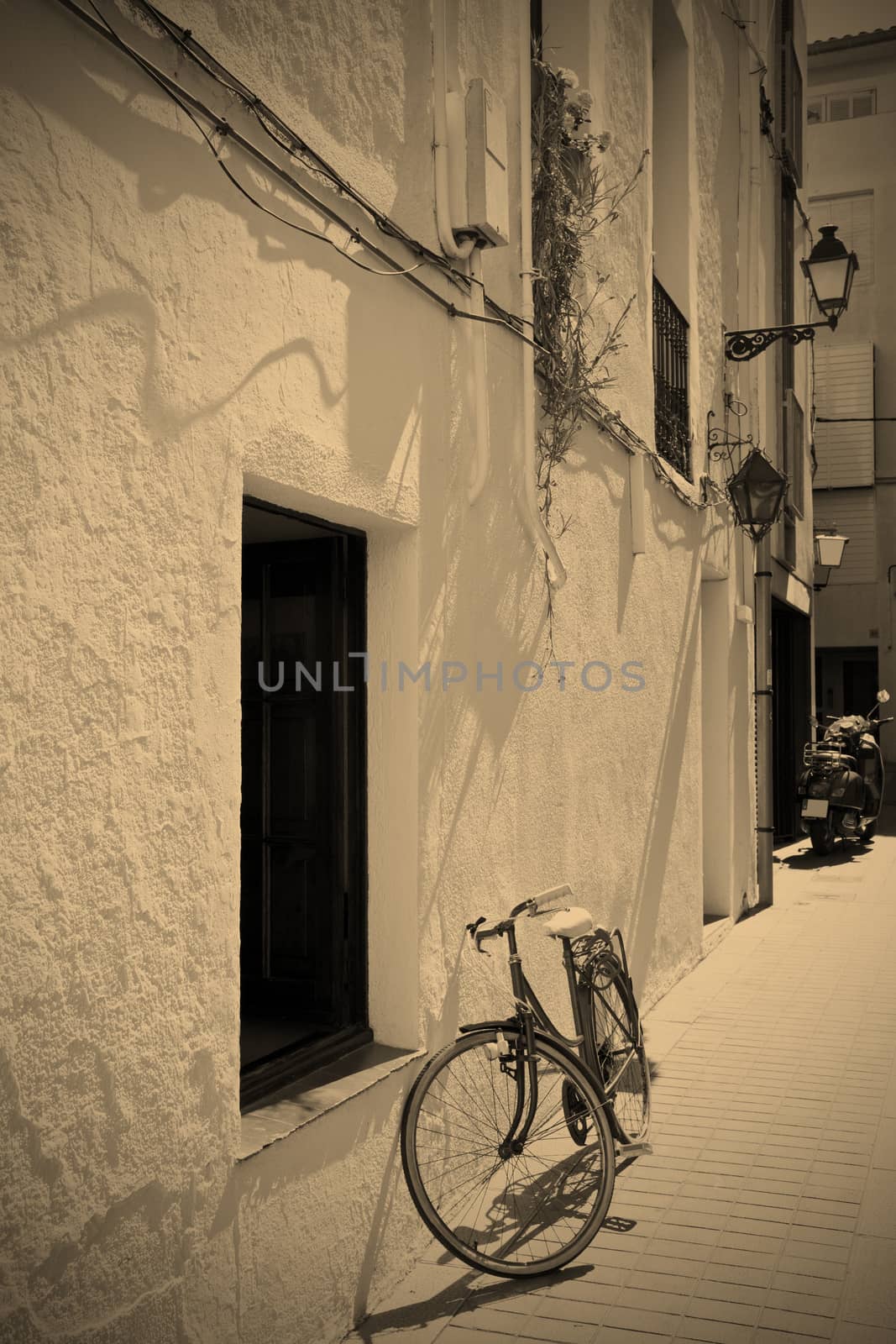 Spanish town street with a bicycle at a white wall, black and white photo, instagram image style