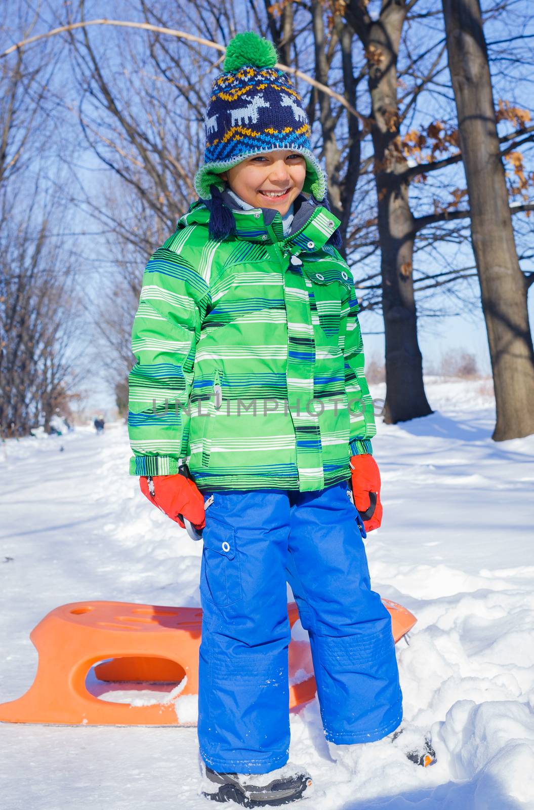 Little boy having fun with sled in winter park by maxoliki