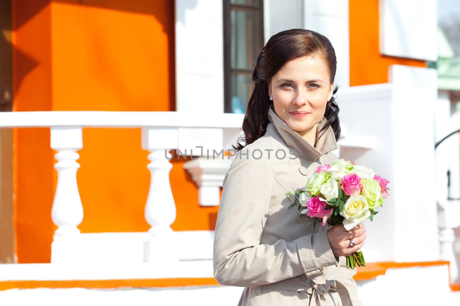 beautiful young woman with a wedding bouquet on a background of vintage architecture