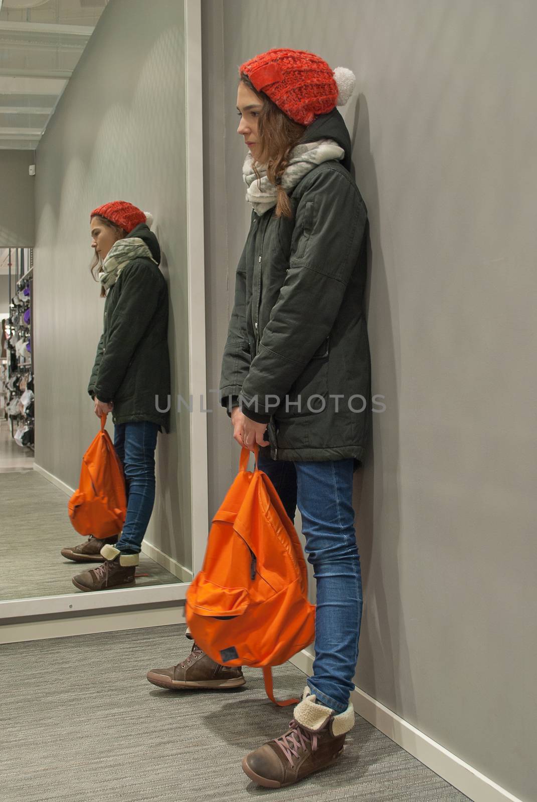 Reflection in the mirror girl in a red cap and orange backpack.