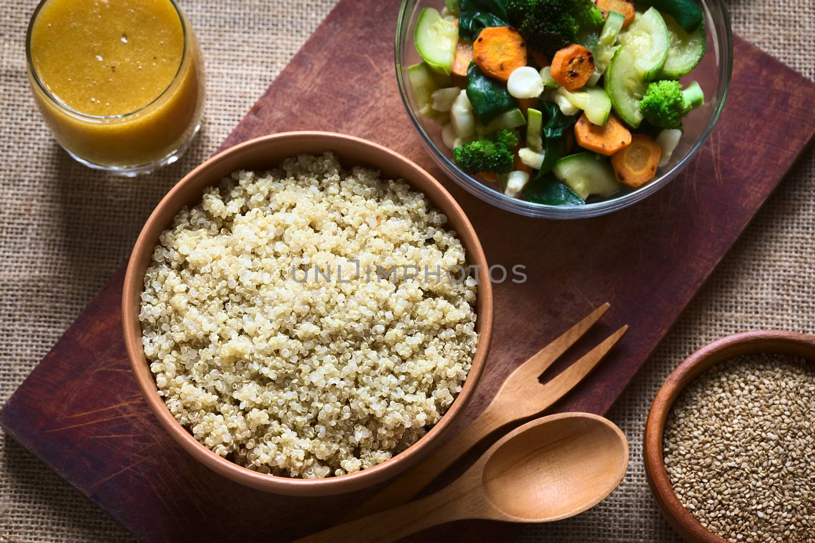 Overhead shot of cooked white quinoa seeds in bowl with sesame, fried vegetables and mango juice photographed with natural light (Selective Focus, Focus on the quinoa)