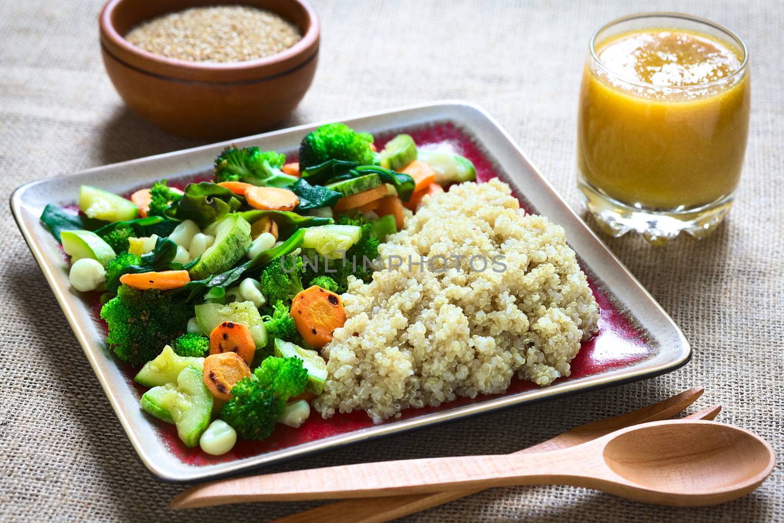 Overhead shot of cooked white quinoa seeds with fried vegetables (carrot, broccoli, spinach, zucchini, corn) and mango juice photographed with natural light (Selective Focus, Focus one third into the dish)