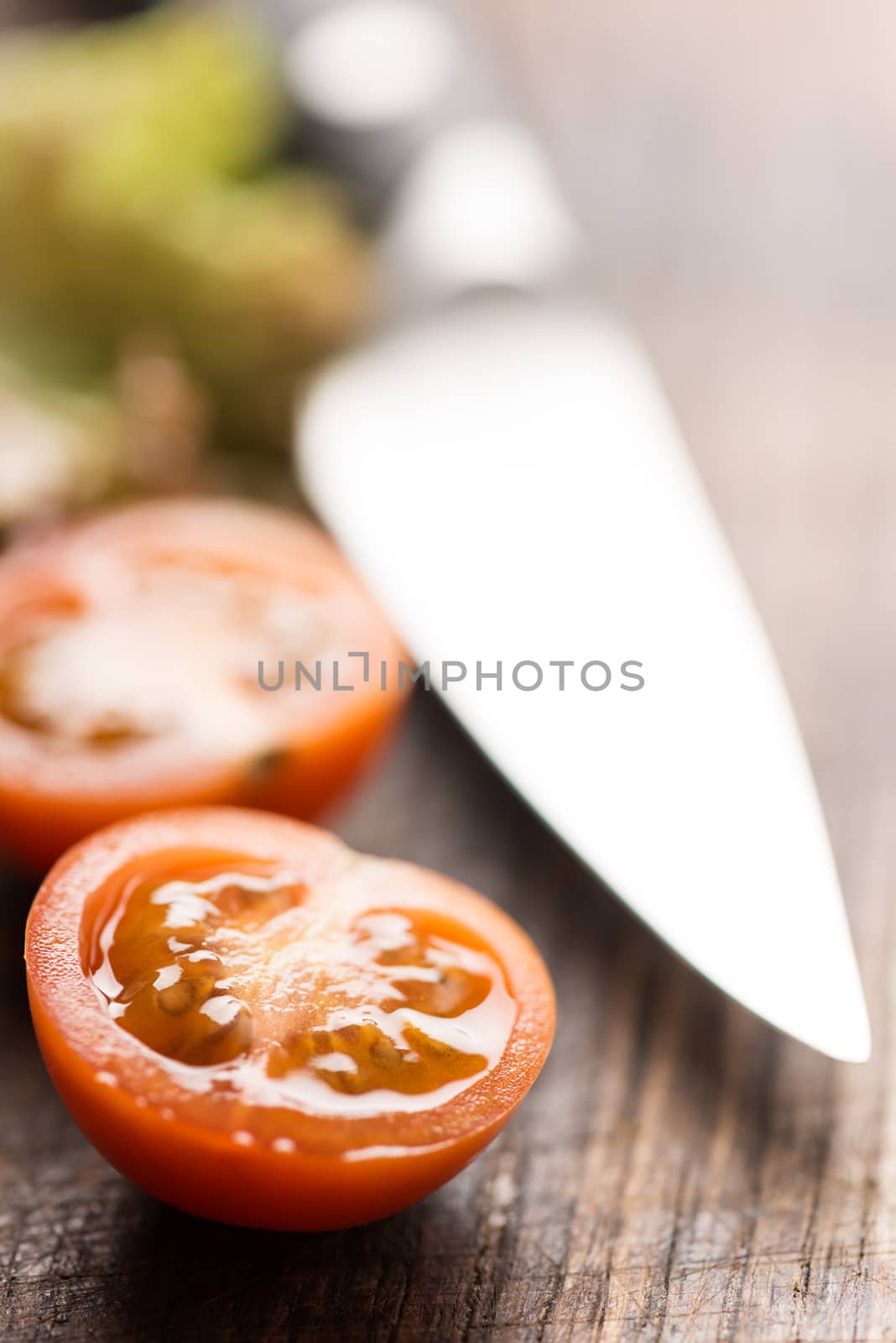 Sliced tomato on cutting board with knife by Nanisimova