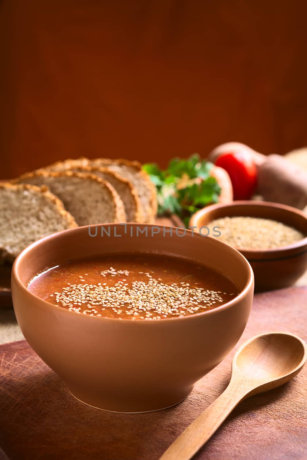 Cream of vegatable soup made of tomato, carrot, potato and parsley served in bowl and sprinkled with sesame seeds, photographed with natural light (Selective Focus, Focus in the middle of the soup)