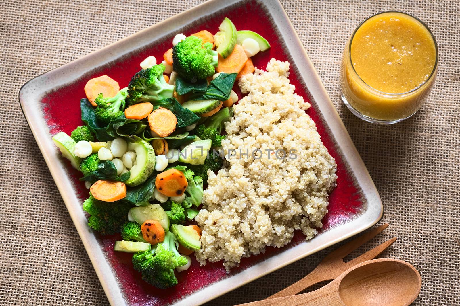 Overhead shot of cooked white quinoa seeds with fried vegetables (carrot, broccoli, spinach, zucchini, corn) and mango juice photographed with natural light