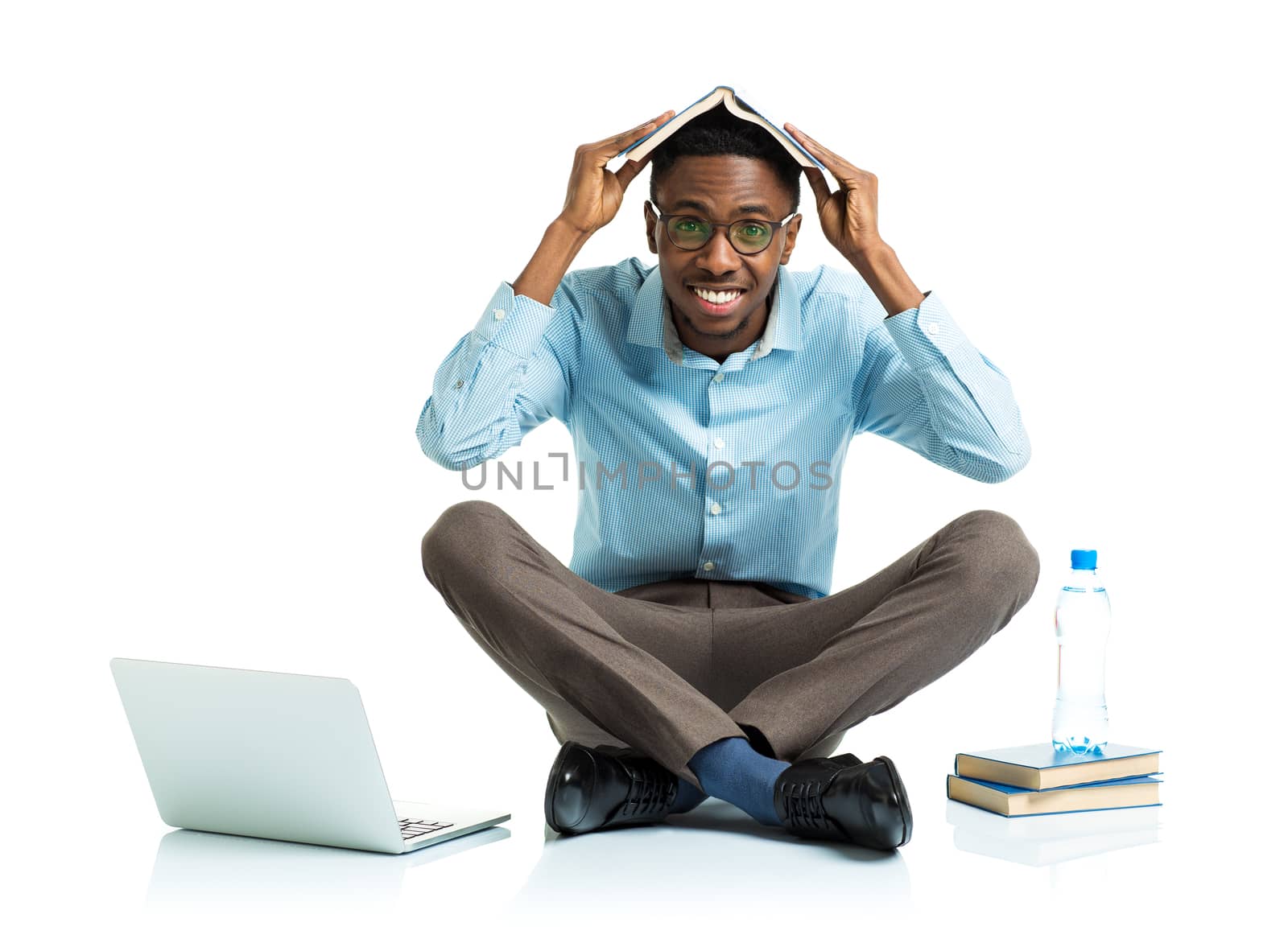 Happy african american college student sitting on white background with laptop and some books