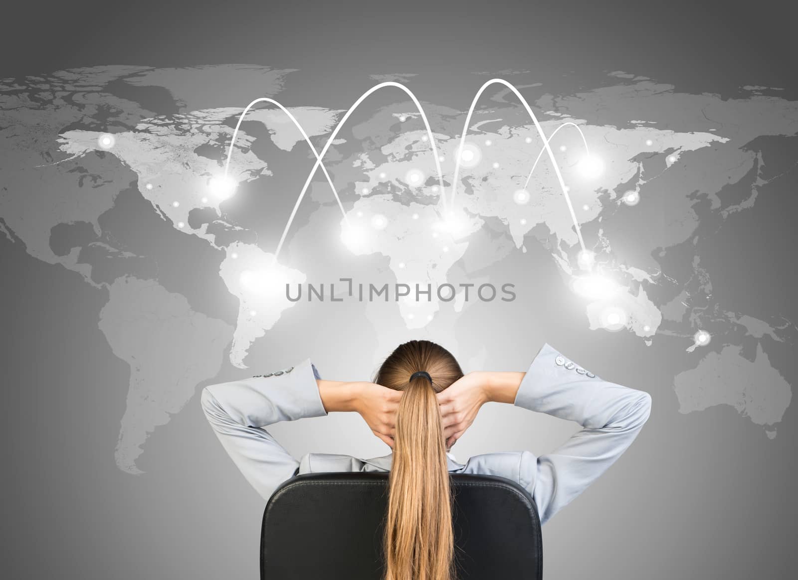 Businesswoman sitting on office chair with hands clasped behind her head, in front of world map and network with lines