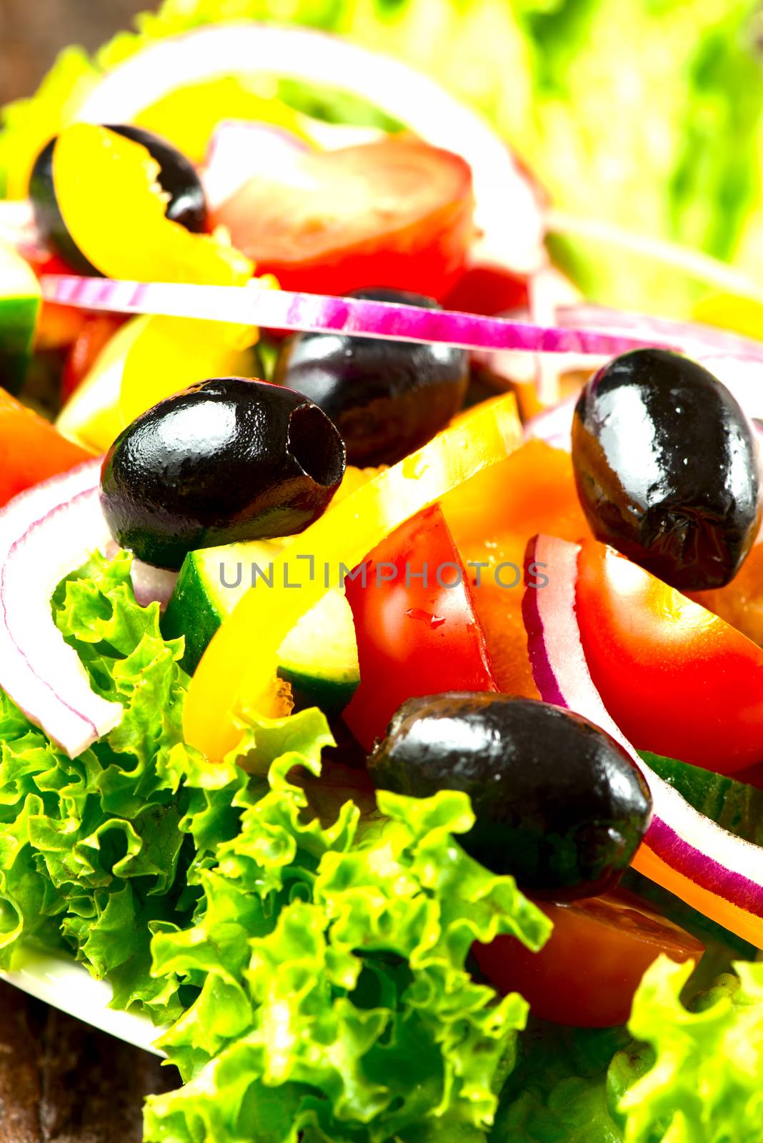 Salad with vegetables and greens in plate close up by Nanisimova