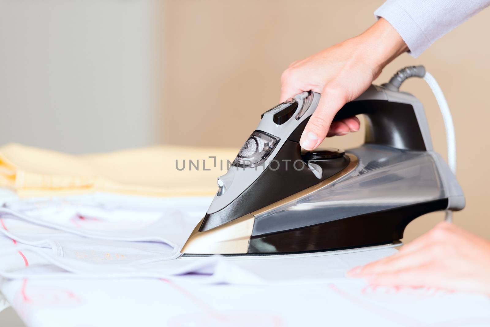 hand of woman ironing clothes on the table close up