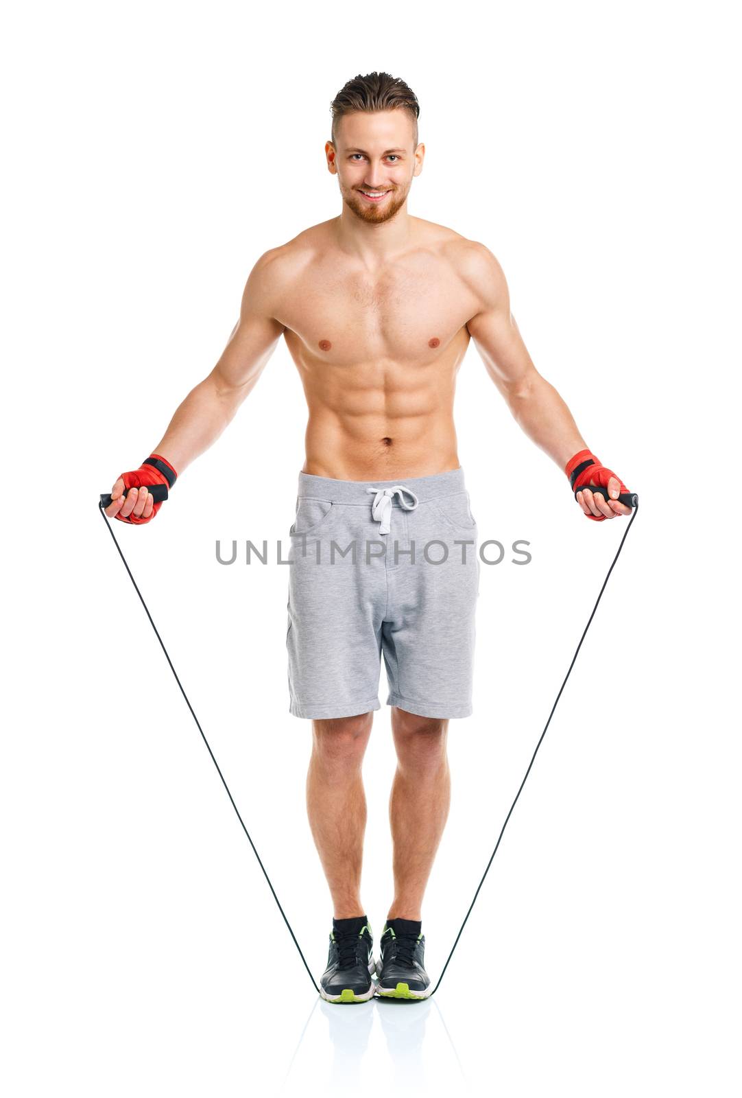 Athletic attractive man jumping on a rope on the white background