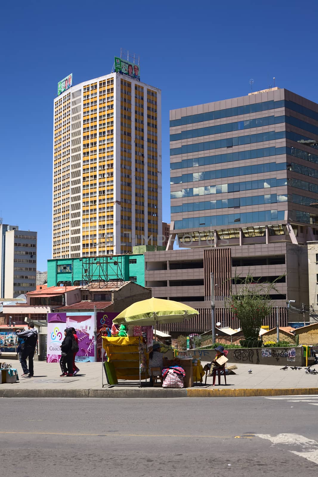 LA PAZ, BOLIVIA - OCTOBER 12, 2014: Unidentified street vender along the Camacho avenue with tall modern buildings in the back in the administrative capital on October 12, 2014 in La Paz, Bolivia 