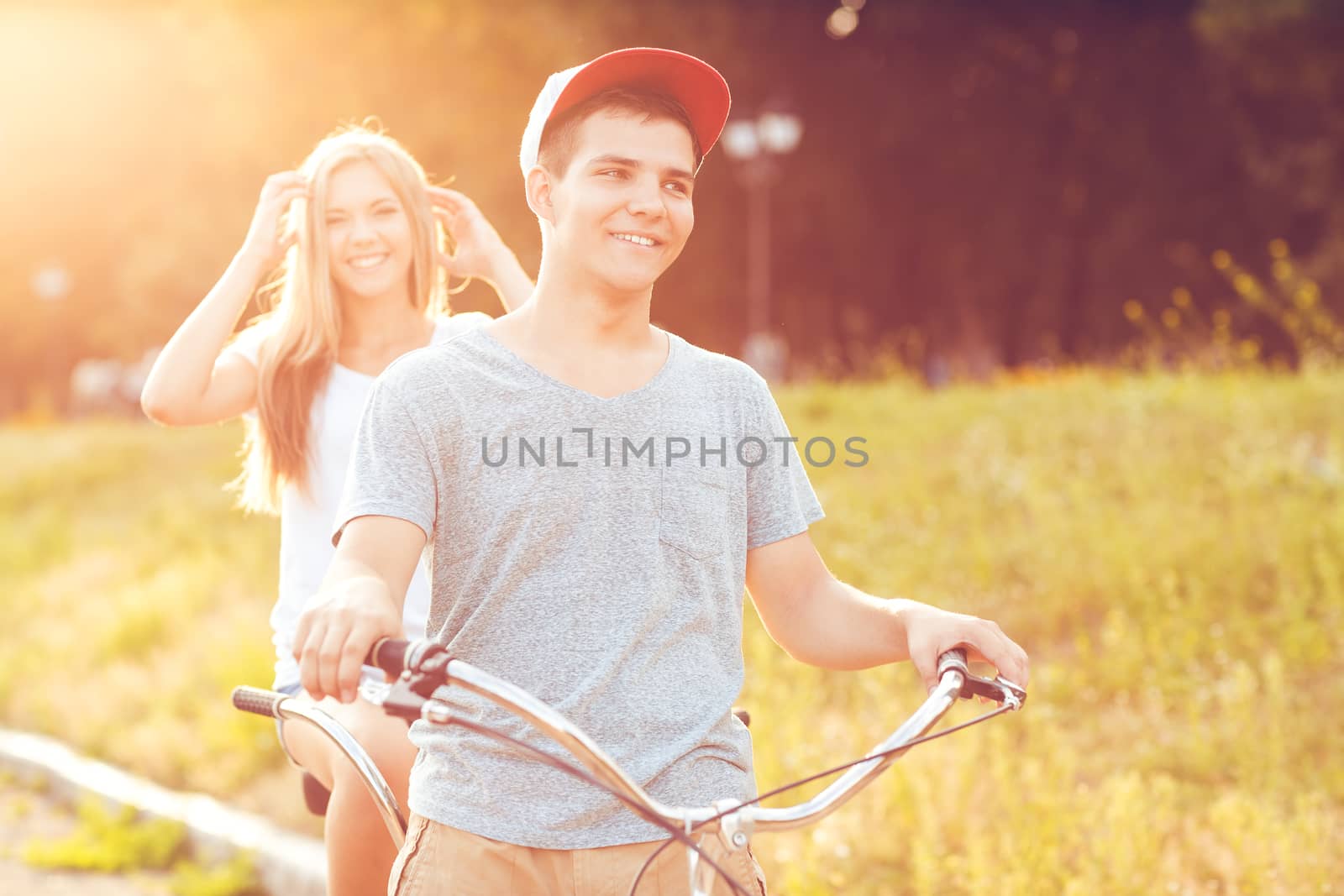Young man and woman riding a bicycle in the park outdoors by vlad_star