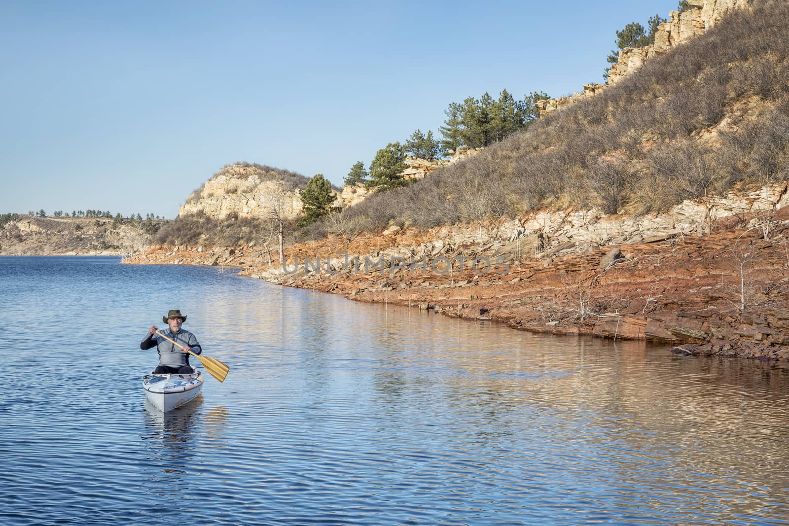 senior male paddling canoe by PixelsAway