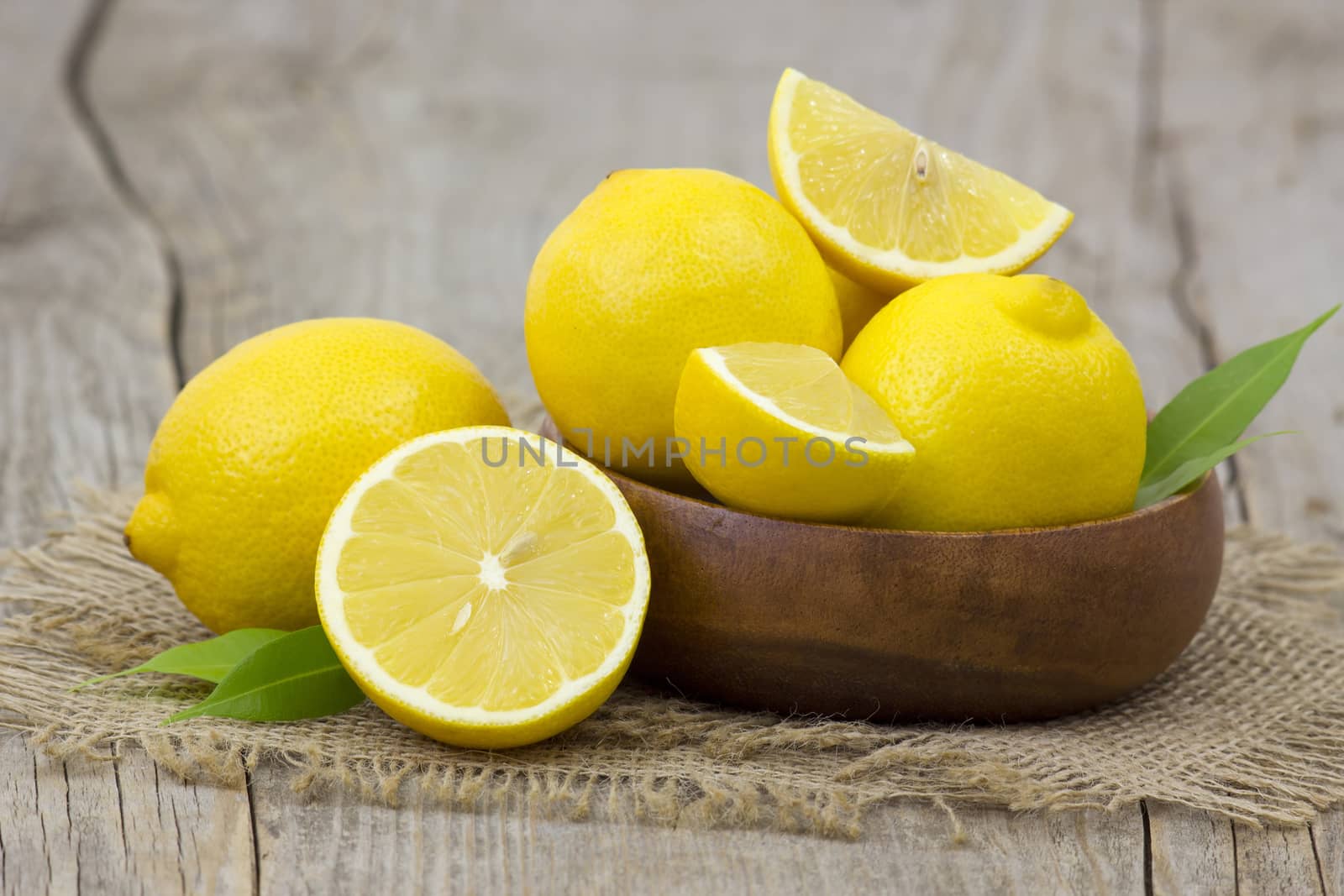 fresh lemons in a bowl on wooden background