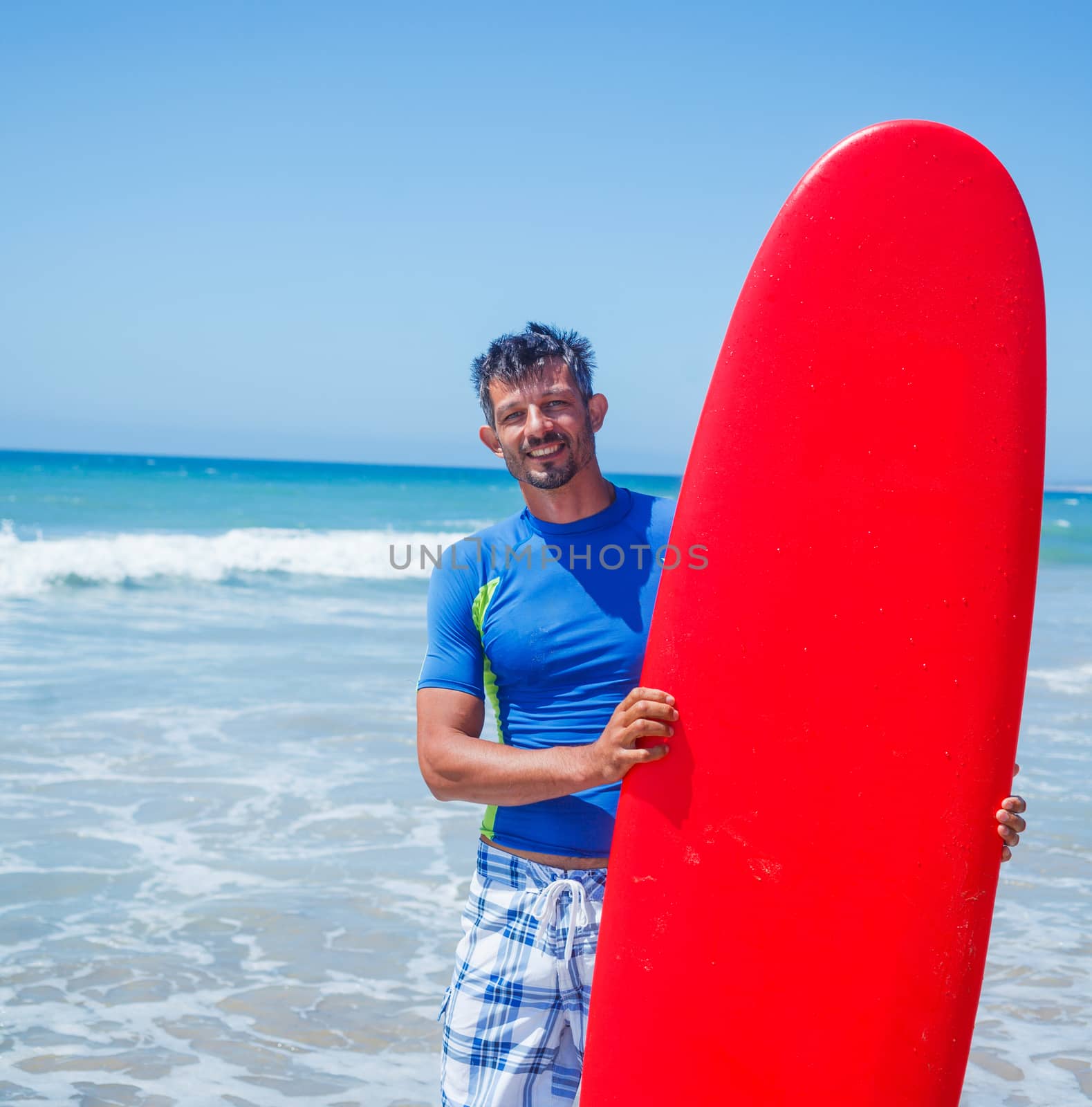 Strong young surf man at the beach with a surfboard.