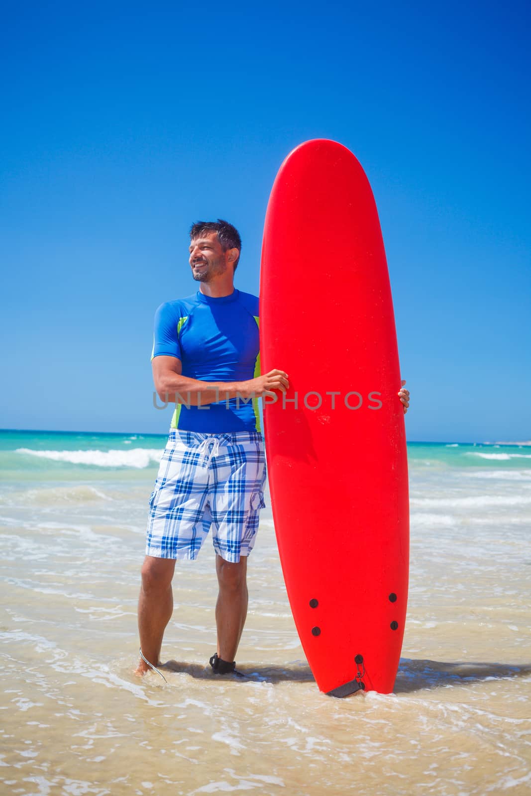 Strong young surf man at the beach with a surfboard.