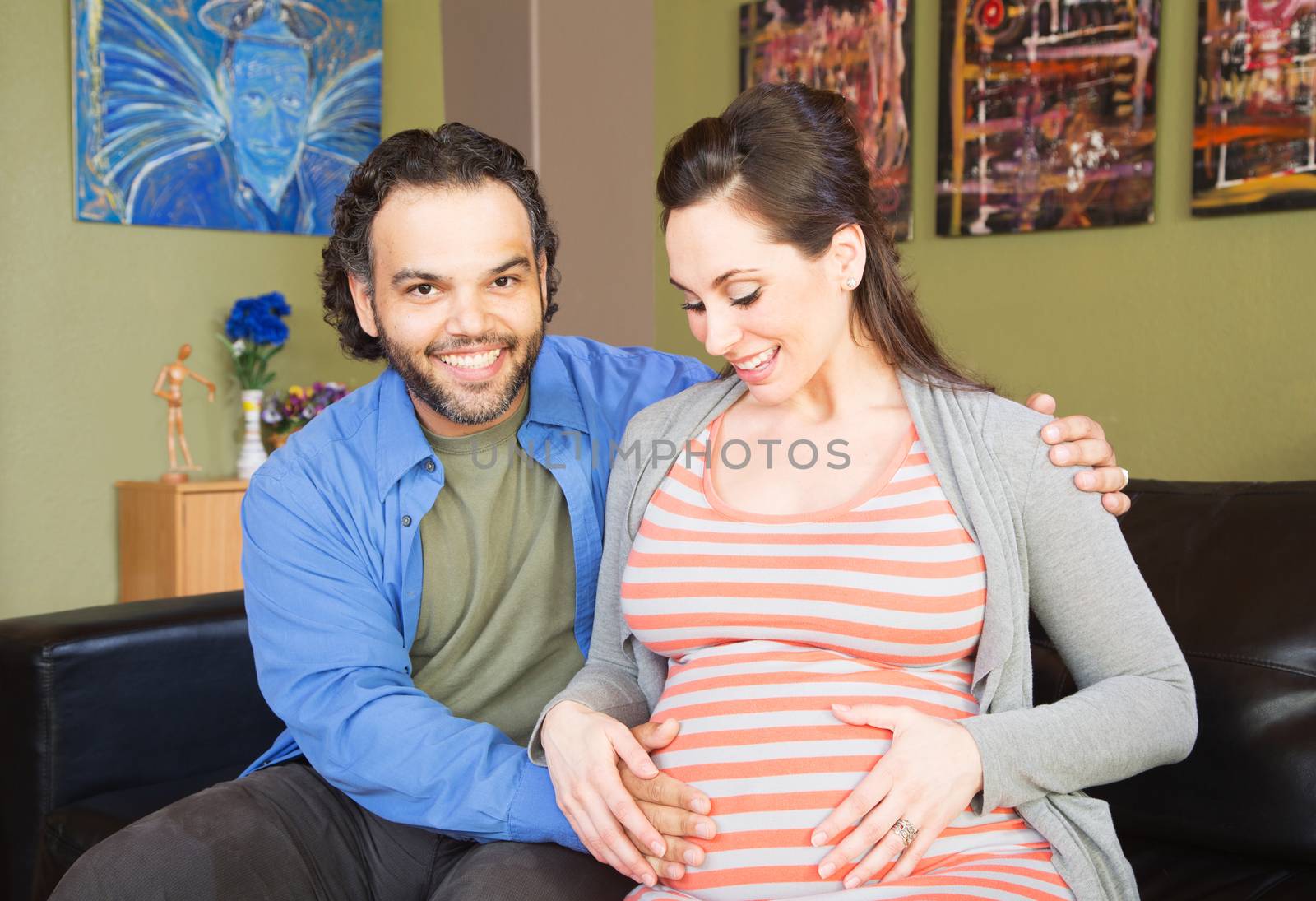 Happy woman touching her pregnant belly with smiling man