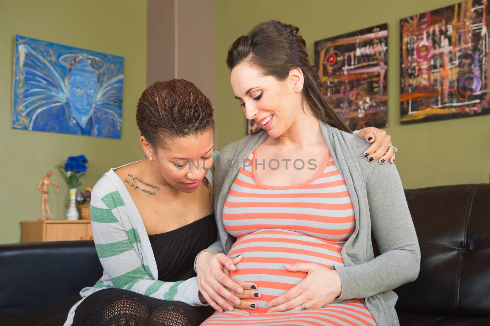 Happy gay female couple looking at womb