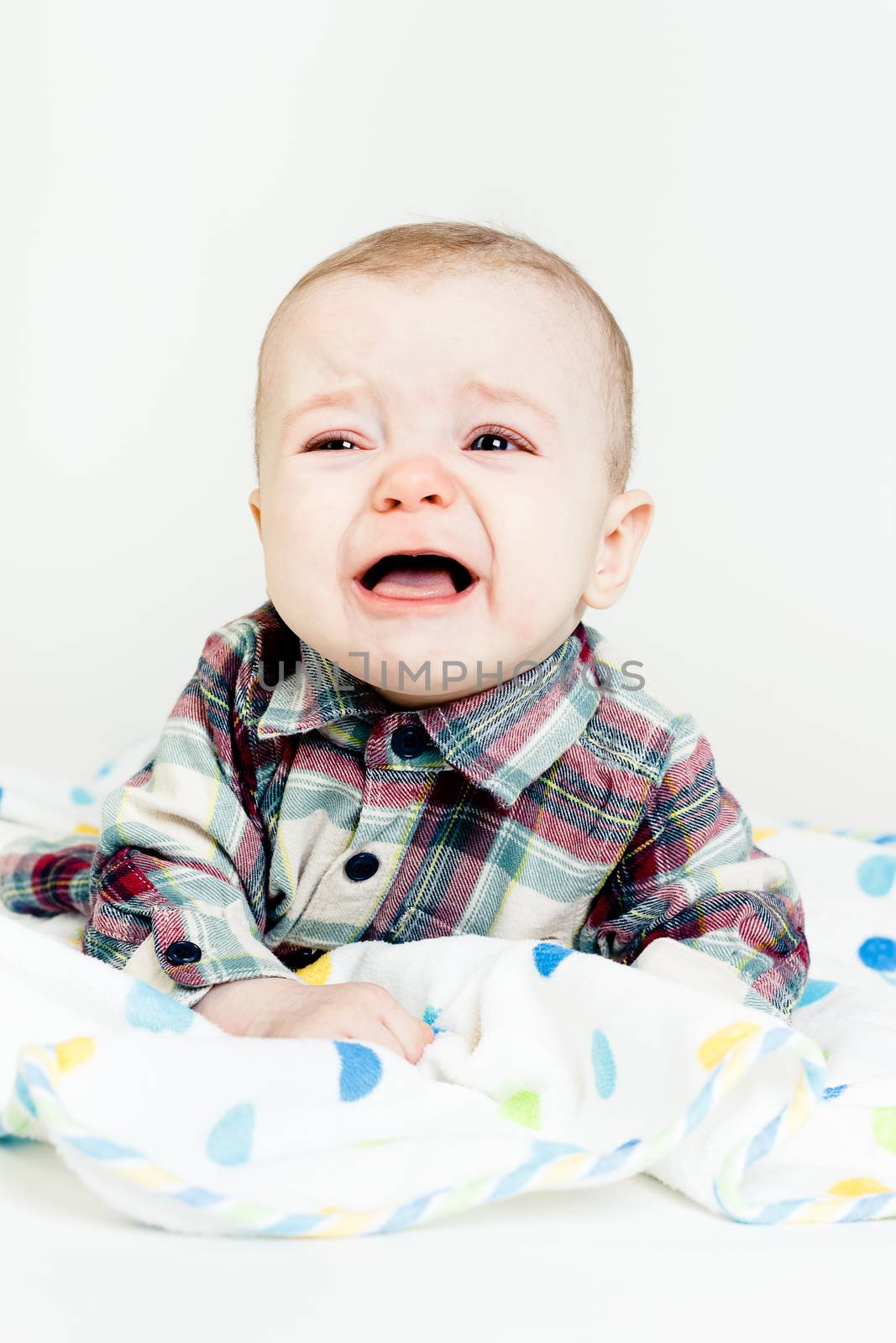 Adorable baby screaming in a plaid shirt. studio photo