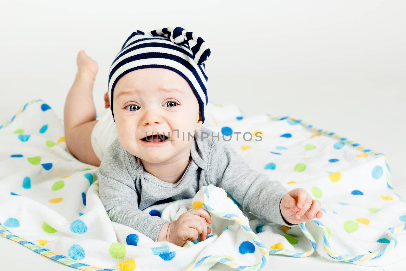 Adorable baby screaming in a striped cap. studio photo
