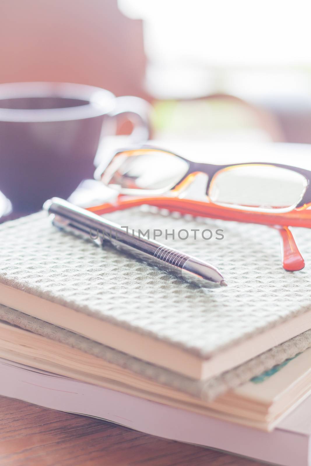 Pen and eyeglasses on three notebooks in coffee shop, stock photo