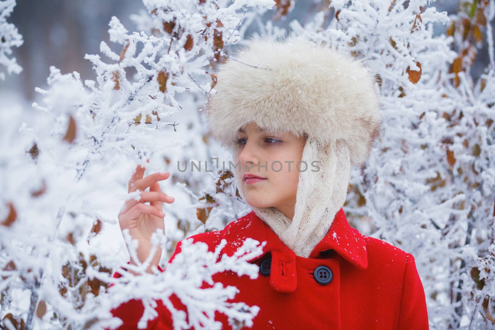 Happy teenager girl in fur hat walking in winter park