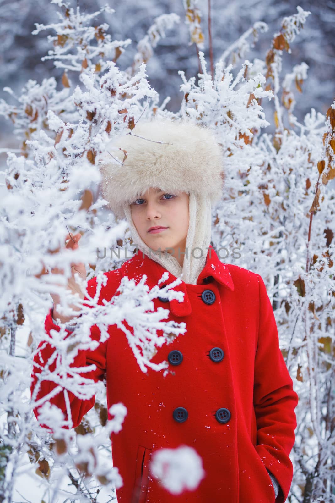 Happy teenager girl in fur hat walking in winter park