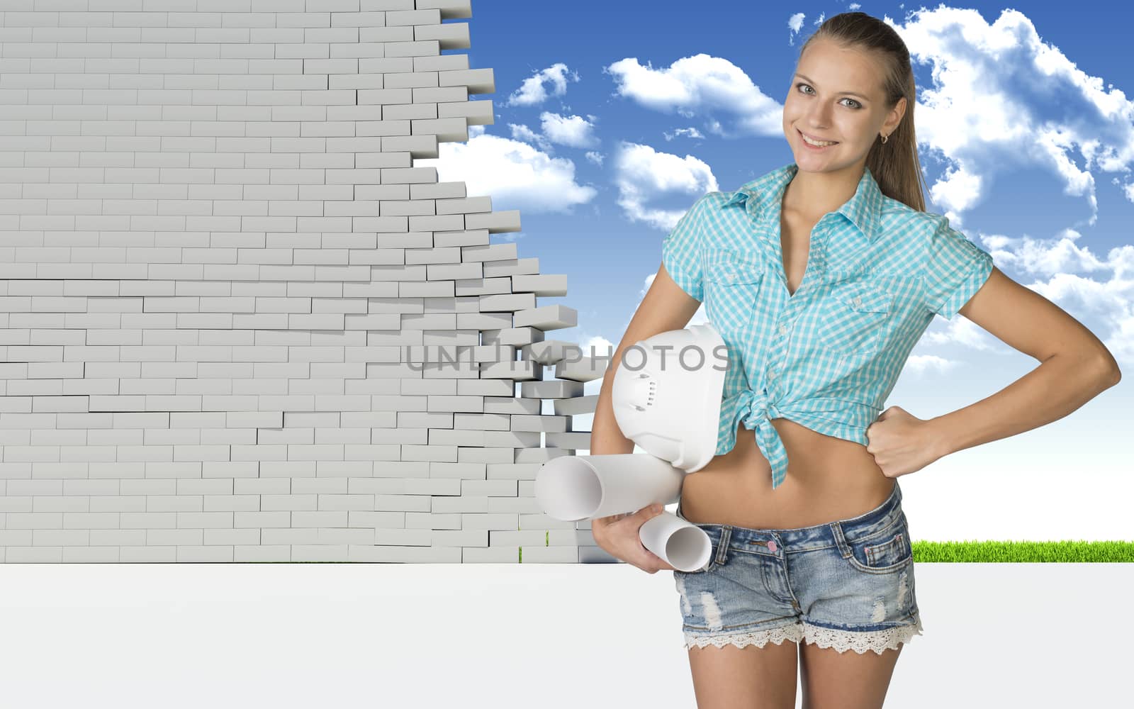 Nice sexy woman holding scrolls of paper and white helmet. Dilapidated brick wall, green meadow with sky as backdrop by cherezoff